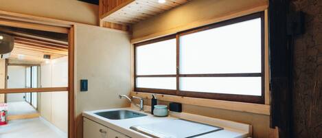 A compact kitchen with a sink, a window, and wooden ceiling beams.