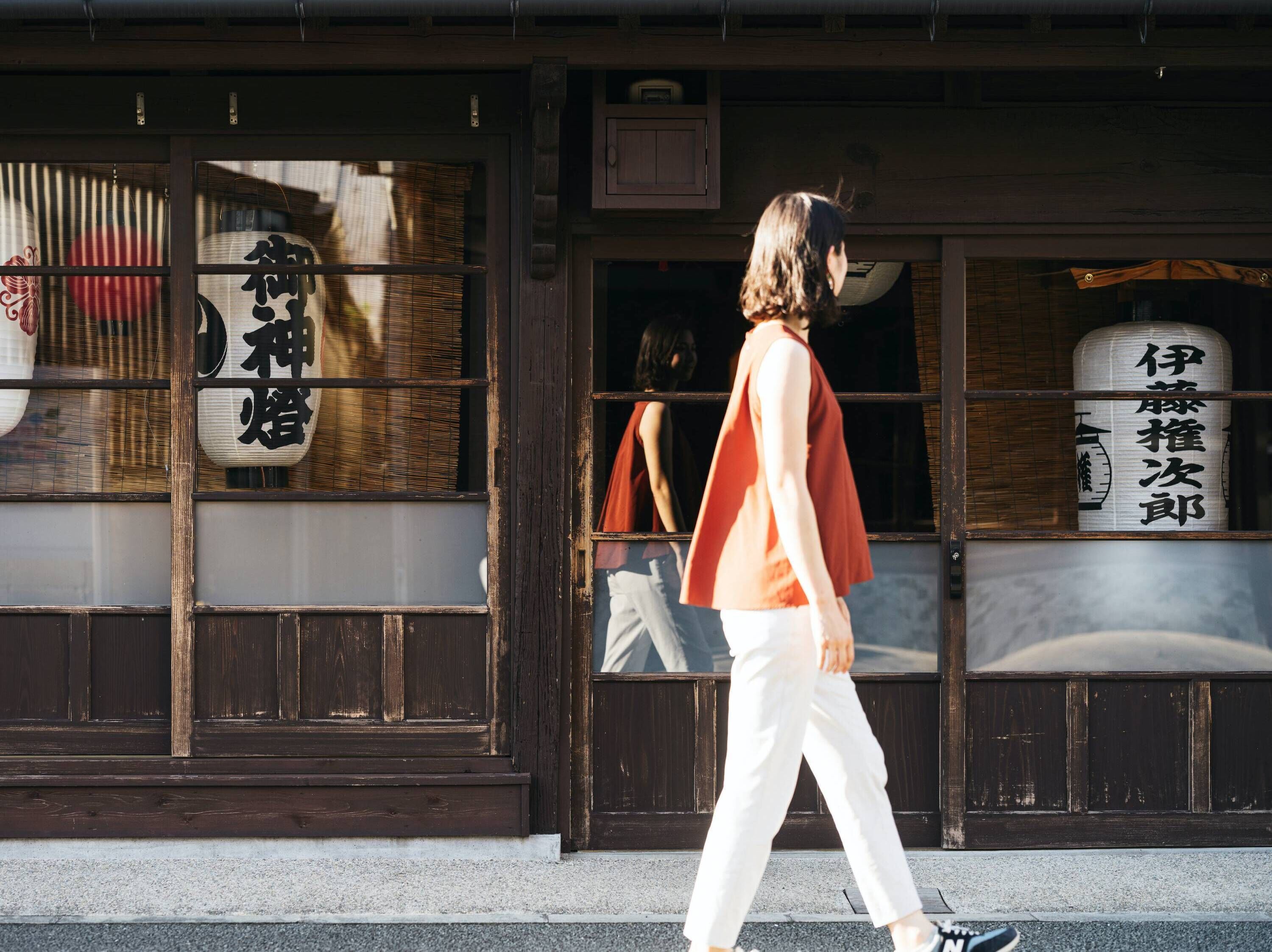 Una persona caminando frente a un edificio con señalización tradicional japonesa y arquitectura de madera.