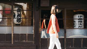 Una persona caminando frente a un edificio con señalización tradicional japonesa y arquitectura de madera.