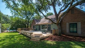 A backyard with a patio, outdoor furniture, and a large tree. - Litchfield Country Club Cottage 4BR 4BA Retreat (Pawleys Island)