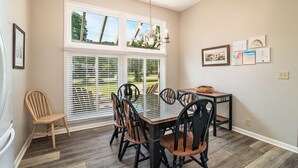A dining area with a glass-top table, black chairs, and a wooden chair. - Litchfield Country Club Cottage 4BR 4BA Retreat (Pawleys Island)