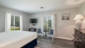 A bedroom with a bed, two chairs, a dresser, a TV, and a lamp. - Litchfield Country Club Cottage 4BR 4BA Retreat (Pawleys Island)