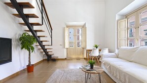 Una sala de estar moderna con una escalera de madera, un sofá, una mesa de centro y un televisor.