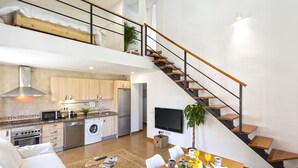 Un loft moderno con cocina, comedor y escalera.