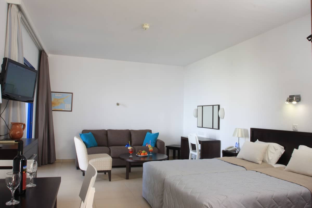 Una habitació d'hotel amb llit, sofà, taula de dinar i televisió.