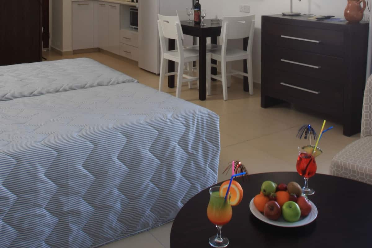Habitació d'hotel compacta amb un llit, una taula de dinar, televisió i petita cuina.