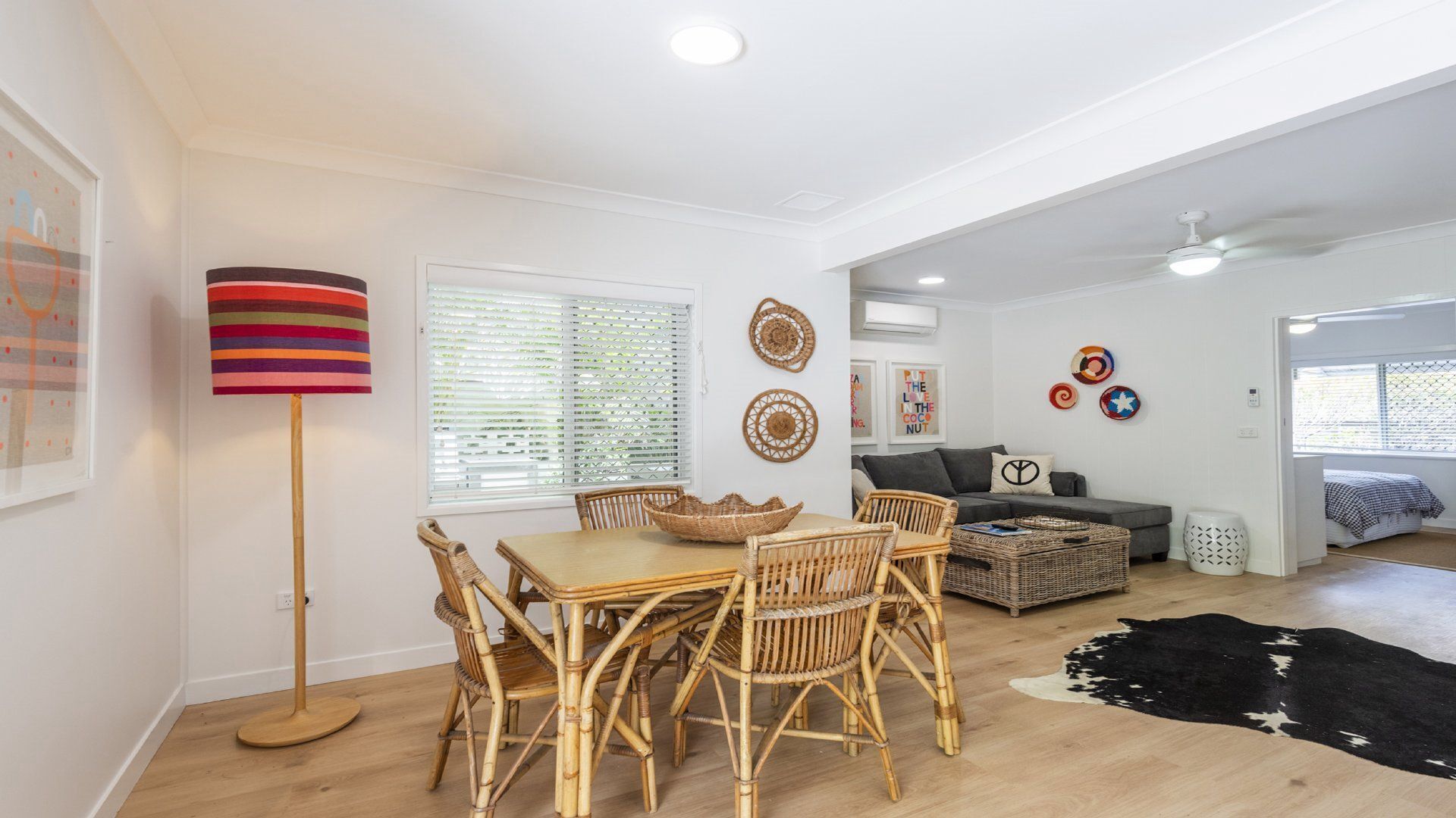 A spacious living area with a dining table and chairs, a sofa, and a ceiling fan.