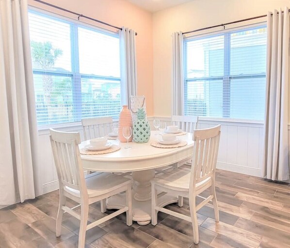Enjoy meals in this dining area with a round table and four chairs, surrounded by large windows and wooden flooring.