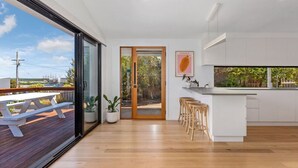 Una cocina moderna con una isla grande, armarios blancos y vistas a una terraza exterior por una puerta corrediza de vidrio.