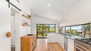 Una cocina moderna con un armario de madera, electrodomésticos de acero inoxidable y un amplio ventanal con vistas a zonas verdes.