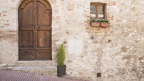 A stone building with a large wooden door and a small window with a flower box. - GARDEN HOUSE (San Gimignano)