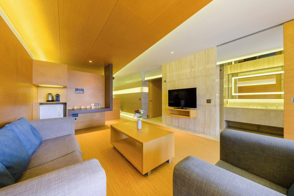 A modern living room with a sofa, coffee table, and a flat-screen TV mounted on the wall.