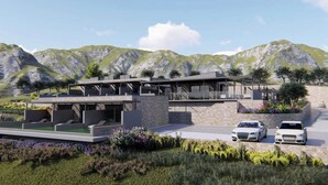 Une maison moderne à deux étages, dotée d’une piscine, entourée d’un jardin aménagé et offrant une vue sur un paysage montagneux.