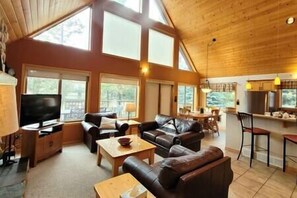 A spacious living area with a large TV, leather sofas, and a dining table.