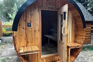 A wooden sauna with a bench inside, a door, and a small sign on the wall.