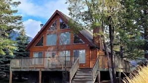 Una baita di legno con un balcone, una scala e un garage.