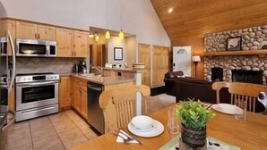 Una cucina con mobili in legno, un camino in pietra e un'area pranzo con un tavolo apparecchiato per due.