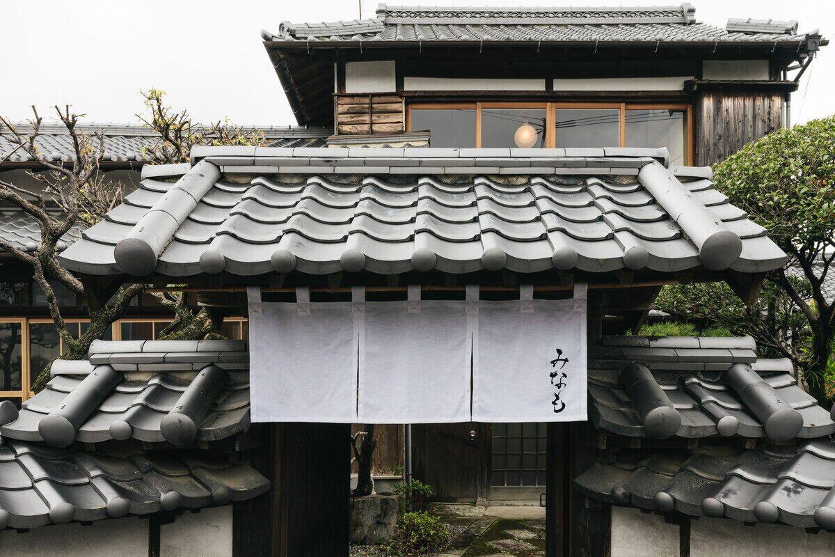 A traditional Japanese building with a tiled roof and a wooden structure in the background.
