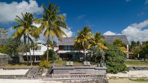 Een strandhuis met moderne architectuur, een zwembad en palmbomen.