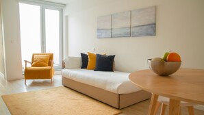 A modern living room with a sofa, a yellow armchair, a wooden dining table, and a fruit bowl. - Select Porto Suites (Porto)