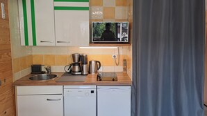 A compact kitchen with a dishwasher, a coffee maker, and a microwave.