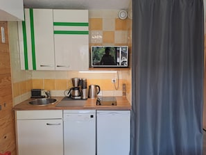 Una cocina compacta equipada con lavavajillas, cafetera y microondas.