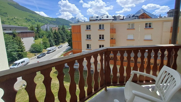 A balcony with a view of a mountain, a road, and buildings.