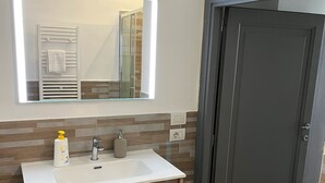 A modern bathroom with a white sink, a mirror, and a towel warmer. - APARTMENT 4 PANTHEON (Roma)