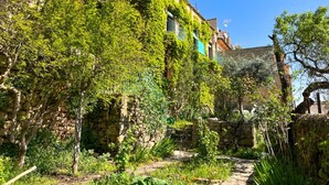 Un edificio de piedra con muros cubiertos de hiedra y un sendero de piedra que lleva a una puerta.
