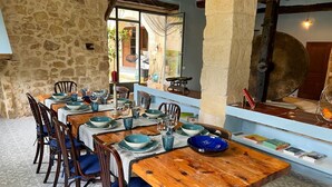 Un comedor con mesas y sillas de madera, paredes de piedra y vistas al exterior.