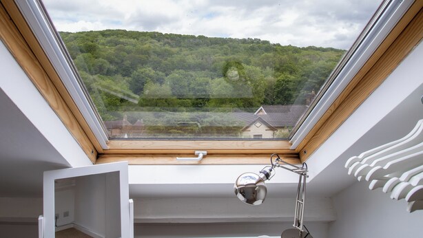 A skylight with a view of a forested hill, a desk with a lamp, and a small white shelf. - Jackfield Old School (Jackfield)