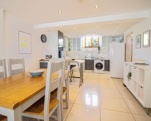 A modern kitchen with a dining area, including a wooden table and white chairs. - Jackfield Old School (Jackfield)