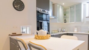 A modern kitchen with a white countertop, stainless steel appliances, and a clock on the wall. - Jackfield Old School (Jackfield)