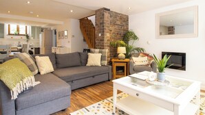 A modern living room with a grey sofa, a white coffee table, and a brick fireplace. - Jackfield Old School (Jackfield)