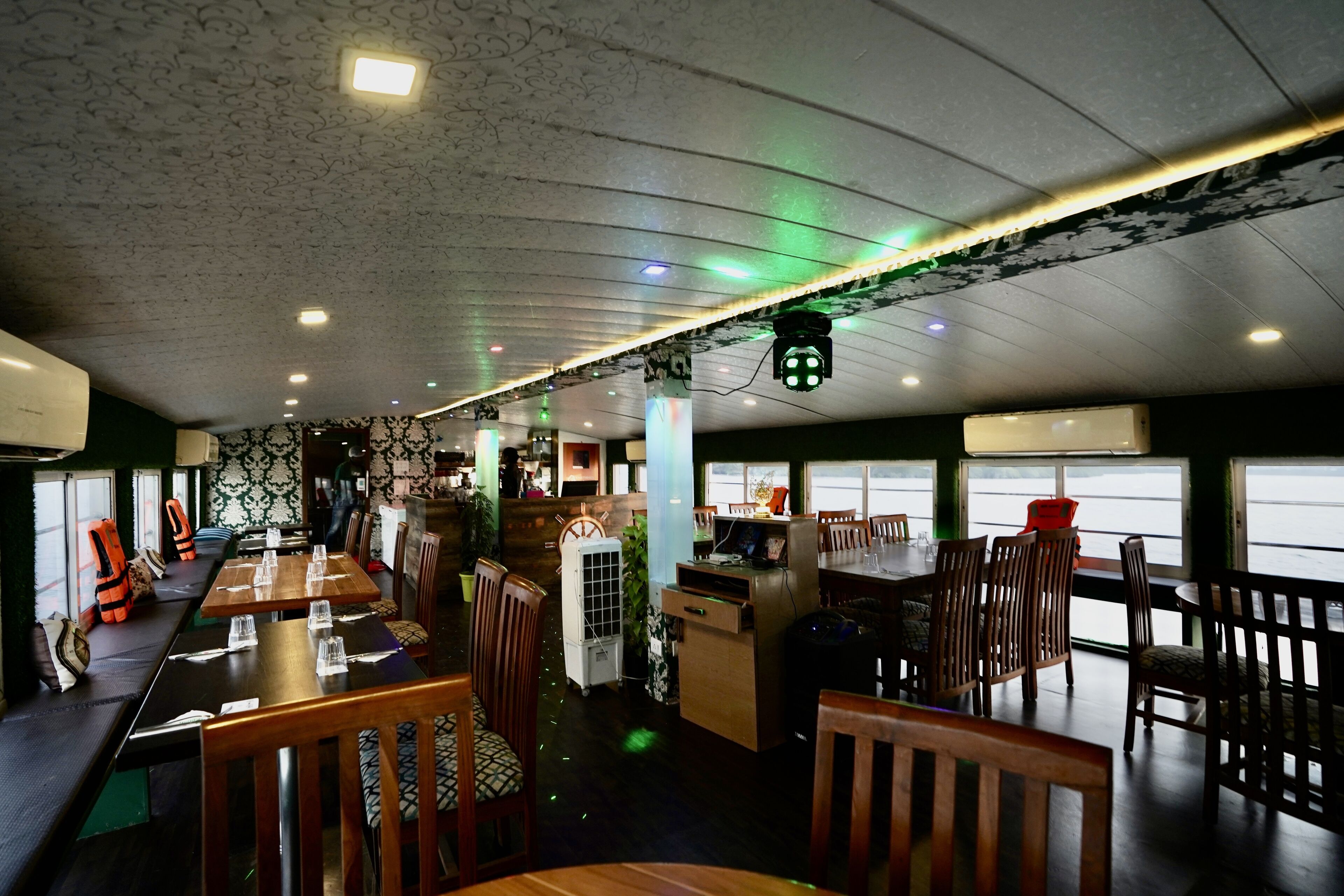 A restaurant with wooden tables and chairs, a white refrigerator, and a patterned wall.