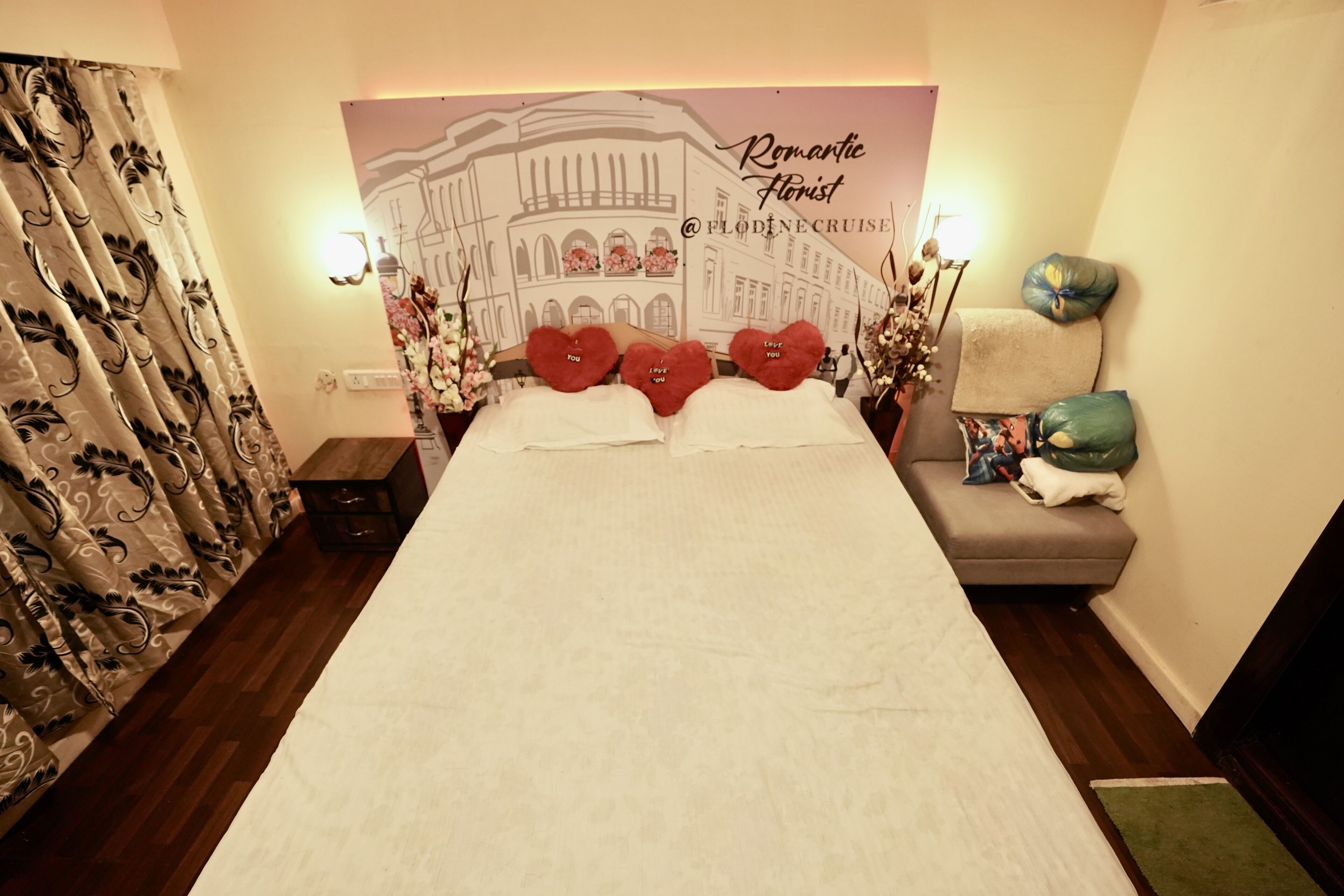A hotel room with a large bed, a sofa, and a decorative headboard with a cityscape mural.