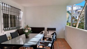 Un balcone con tavolo e sedie in vetro, una pianta in vaso e vista sui palazzi.