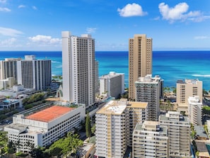 A high-rise hotel with multiple floors, a swimming pool, and a view of the ocean.