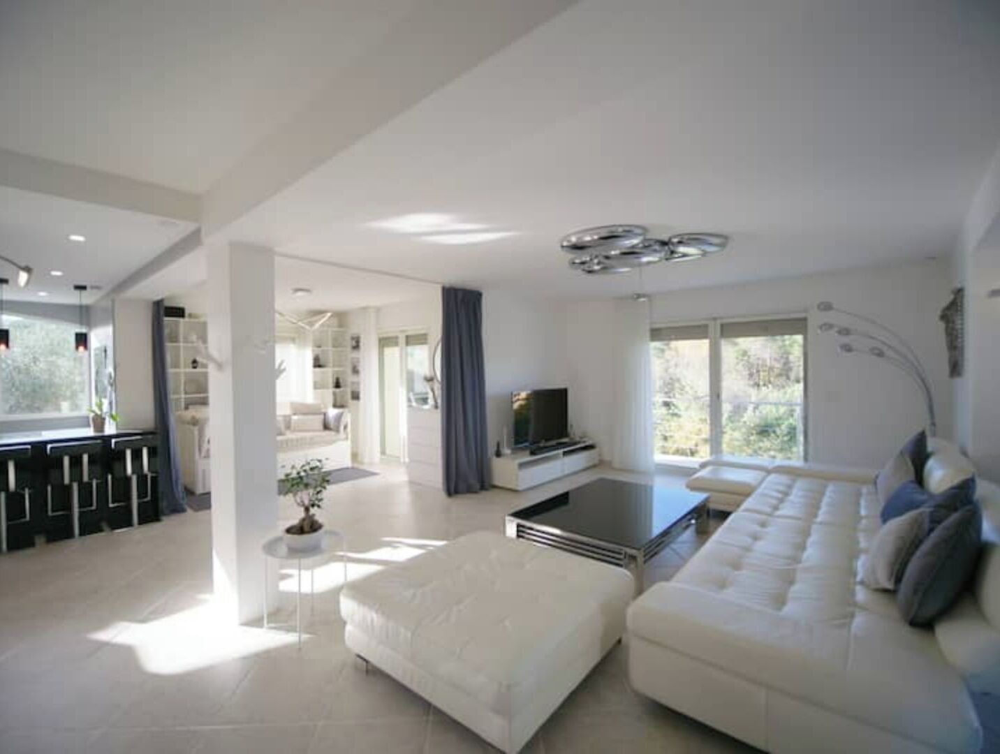 Ein modernes Wohnzimmer mit einer Couch, einem Couchtisch und einem Fernseher. Eine Treppe führt zu einer weiteren Ebene, und ein Balkon bietet einen Ausblick.