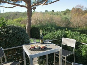 Une table à manger en plein air, avec des chaises, une bouteille de champagne et des plats remplis de nourriture.