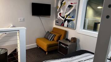 A modern room with a bed, a sofa, a TV, and a painting on the wall.