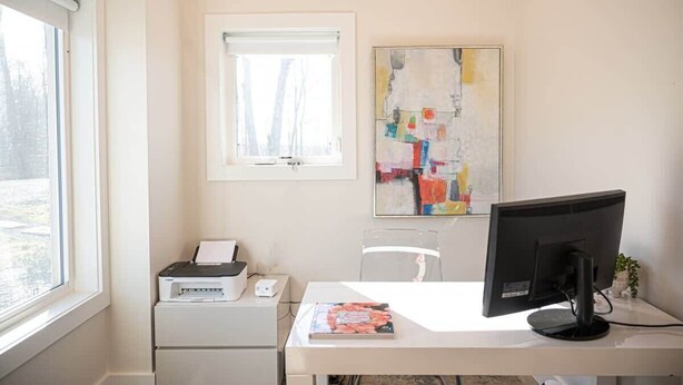 A room with a desk, a printer, a computer monitor, a window, and a painting on the wall. - The Gathering Barn by Buffalo Mountain Getaway (Meadows of Dan)