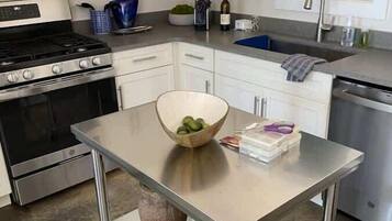 A modern kitchen with stainless steel appliances, a central island, and white cabinetry.