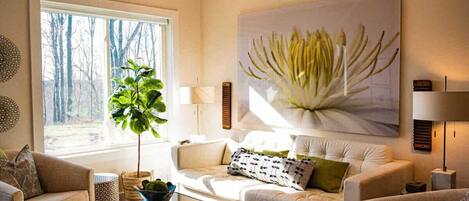 Een zithoek met een bank, een salontafel, een plant en een groot schilderij aan de muur.