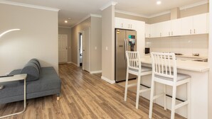 A modern kitchen with white cabinets, a stainless steel refrigerator, and a wooden floor. - Modern 4X2 Perth house near Stadium/Casino/Airport (Cloverdale)