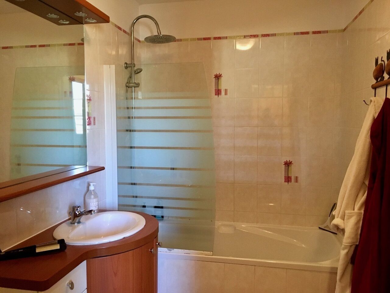Baño con lavamanos, espejo, ducha y bañera.