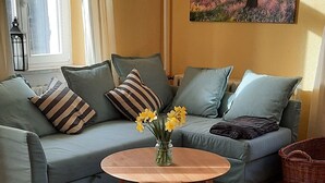 Un salon avec un canapé, une table basse, un tableau et une fenêtre avec des rideaux.