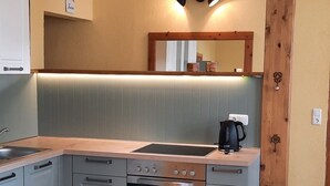 Une cuisine moderne avec des meubles gris, un plan de travail en bois et un four encastré.