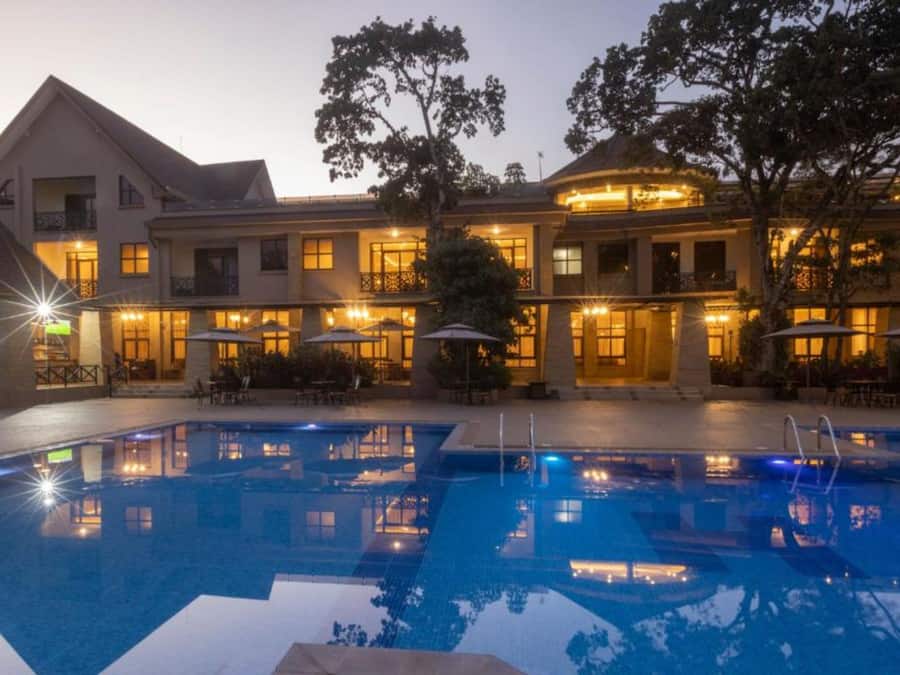 A hotel with a large outdoor swimming pool, multiple balconies, and outdoor seating areas.