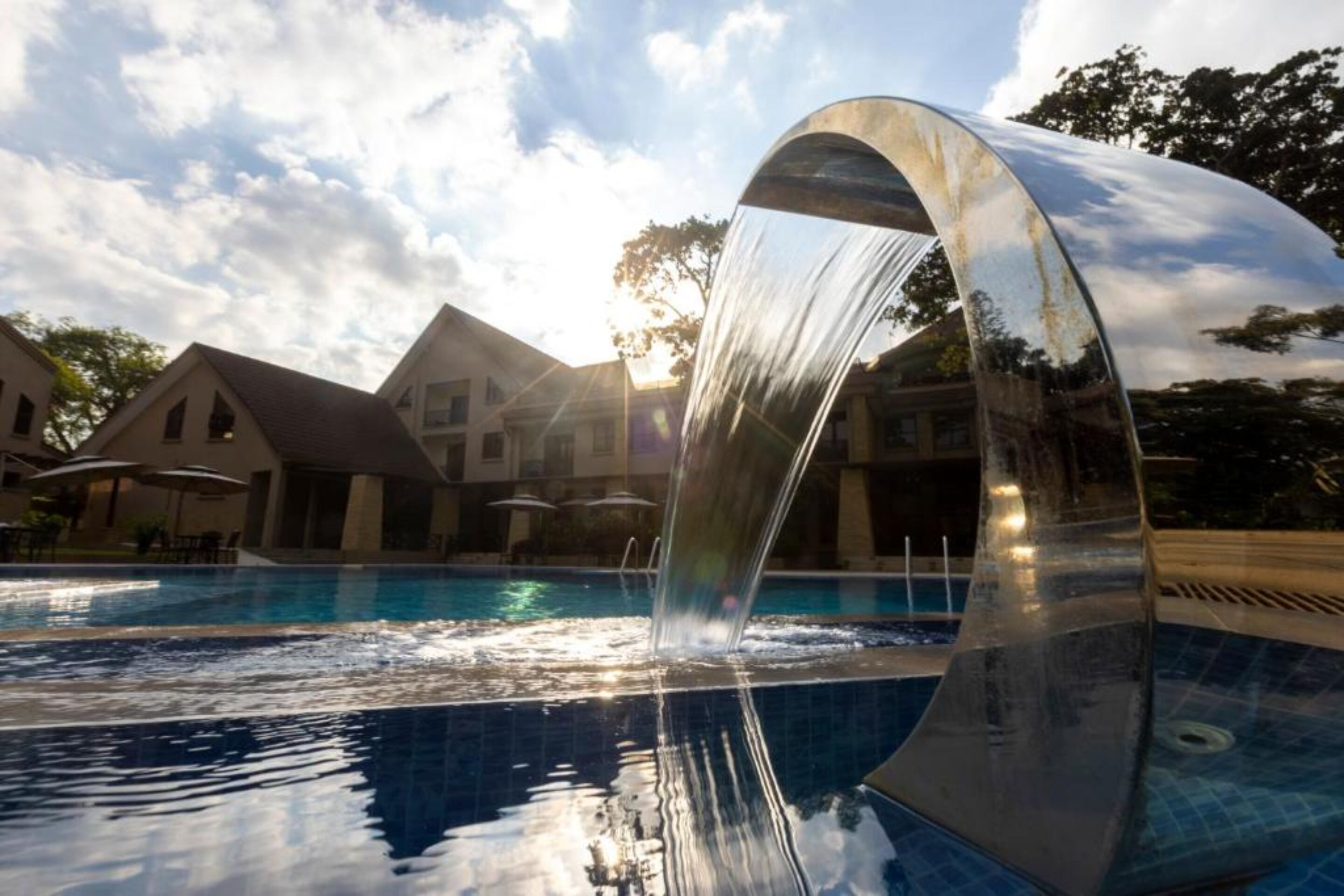 Una piscina con un moderno elemento acuático, rodeada de edificios de estilo arquitectónico clásico.